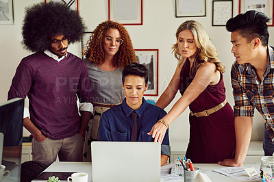 Buy stock photo Shot of a group of designers working together on a laptop in an office