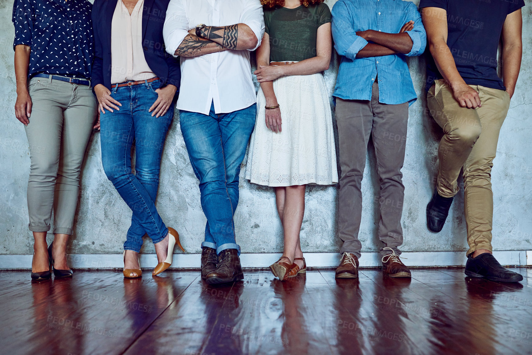 Buy stock photo Shot of an unrecognizable group of businesspeople standing against a wall in an office