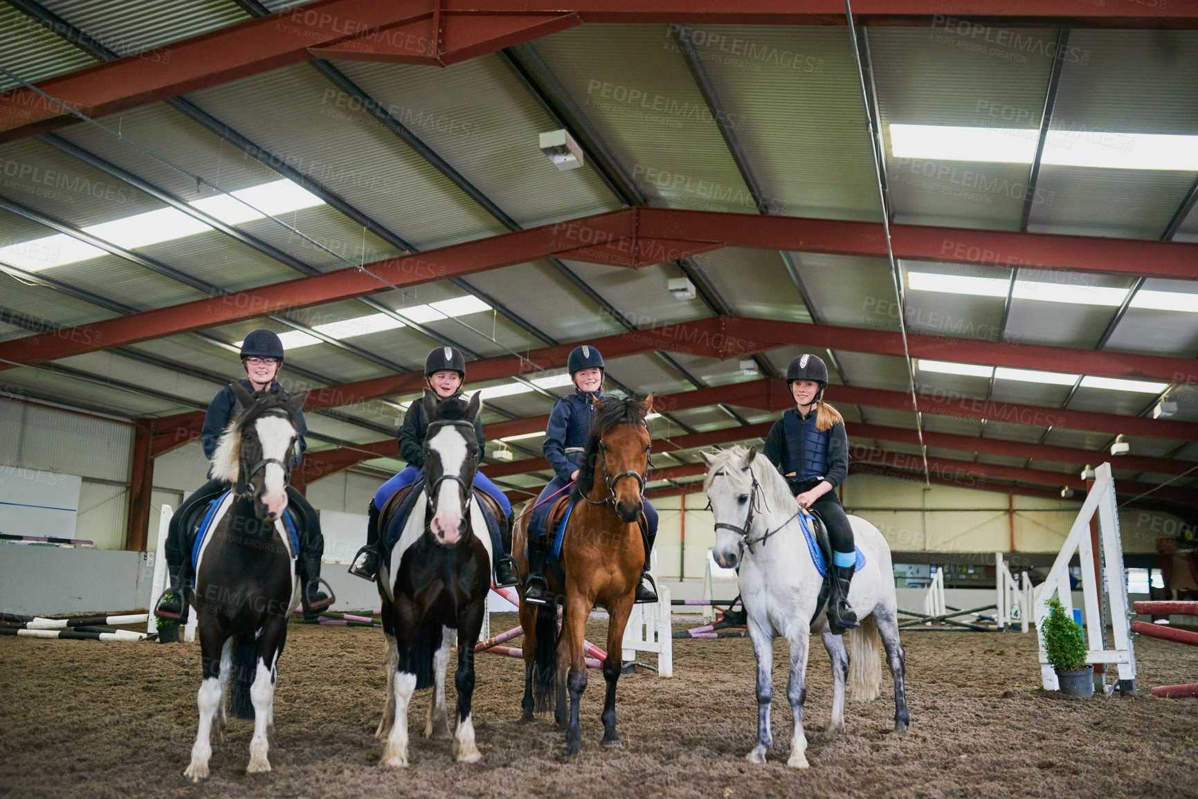 Buy stock photo Shot of young girls sitting on their horses indoors