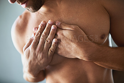 Buy stock photo Shot of a shirtless unrecognizable man holding his chest in discomfort due to pain inside at home