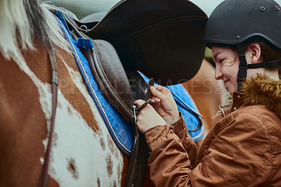 Buy stock photo Horse, girl and prepare saddle outdoor for race, sport and training at countryside ranch. Animal, equestrian and adjust seat for riding with pet for safety, care and protection with happy teenager