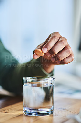 Buy stock photo Shot of an unrecognizable person putting a dissolvable tablet in a glass of water while being seated at a desk in the office