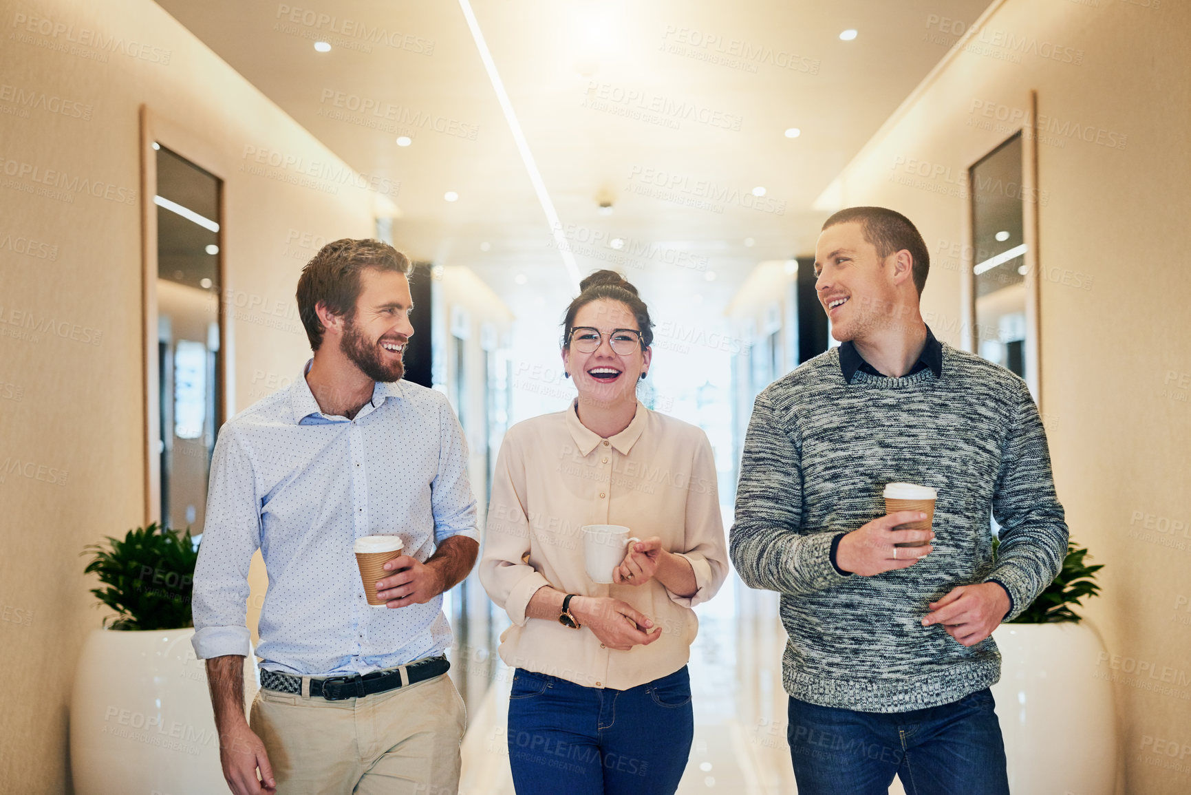 Buy stock photo Portrait of a group of young businesspeople walking together down a passage while drinking coffee