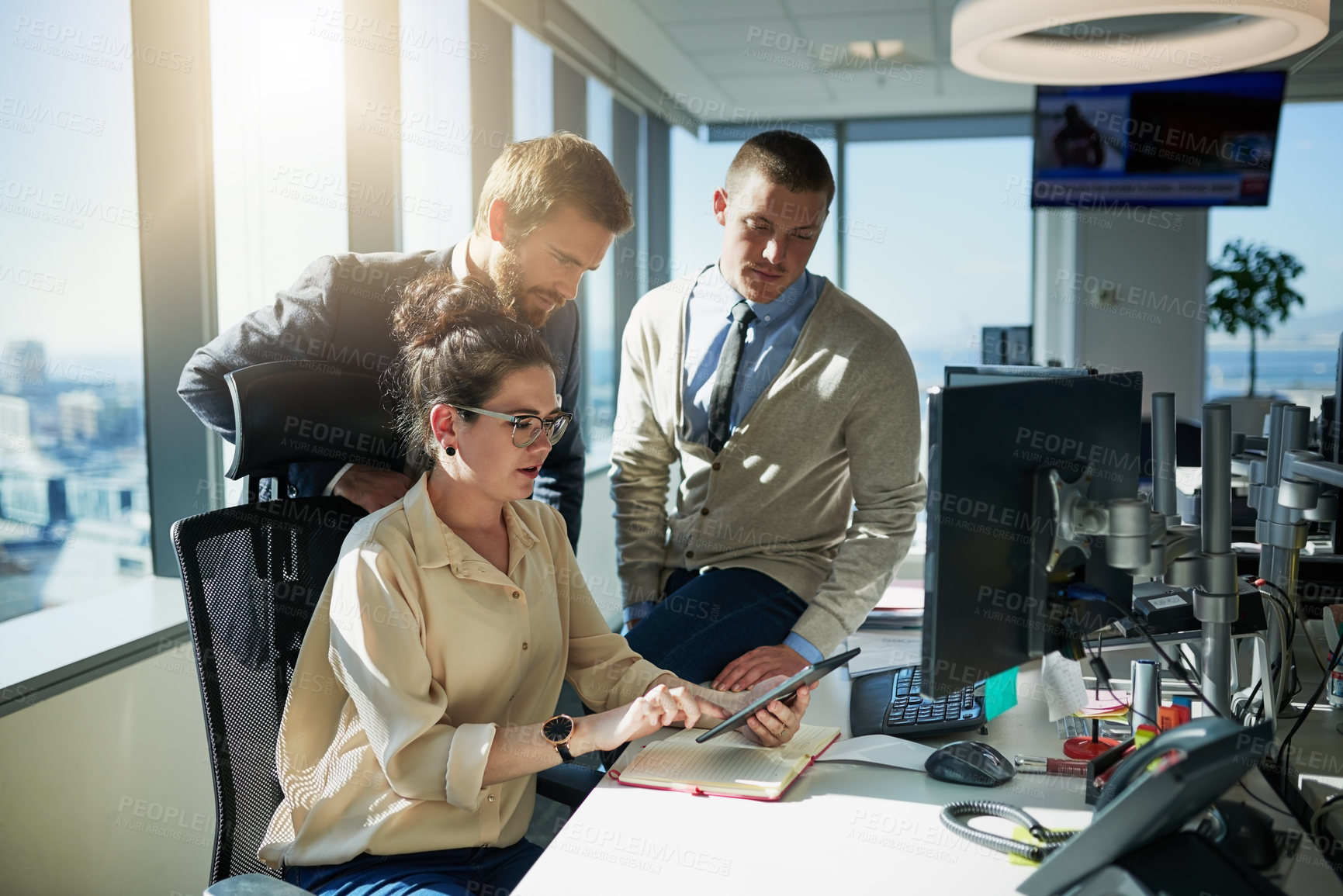 Buy stock photo Shot of a group of young businesspeople working together on a computer inside of the office during the day