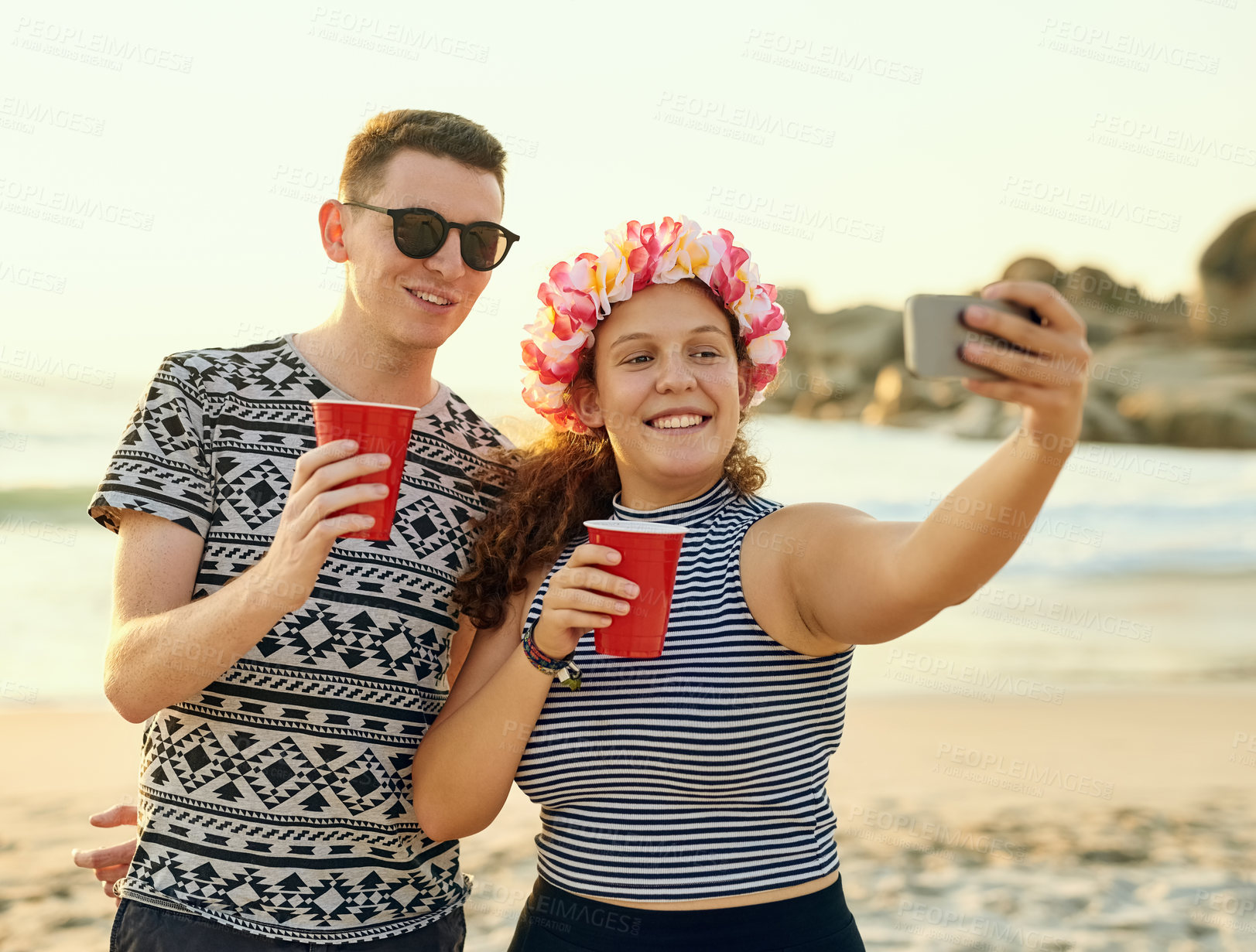 Buy stock photo Shot of a young couple hanging out at the beach