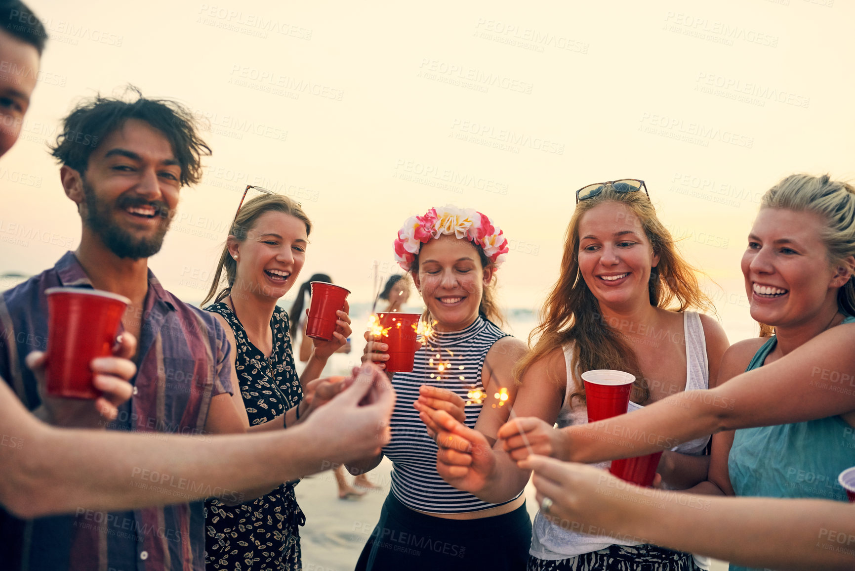 Buy stock photo Group, sparklers and beach with happy friends at sunset party for summer, vacation or holiday in nature together. New years, drinks and celebration with people, bonding and drinking by Miami sea