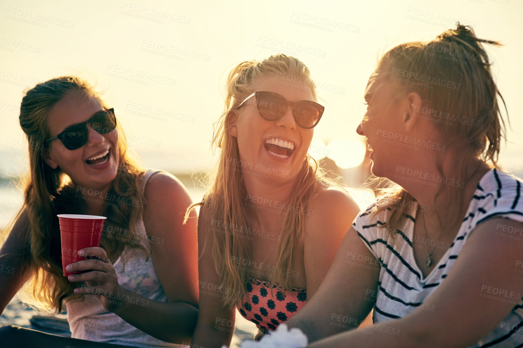 Buy stock photo Friends, drinks and beach with funny joke at party hangout for summer, vacation or holiday in nature together. Laughing, alcohol or celebration with women, bonding and drinking by Miami ocean