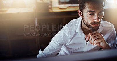 Buy stock photo High angle shot of a handsome young businessman looking thoughtful while working late in the office