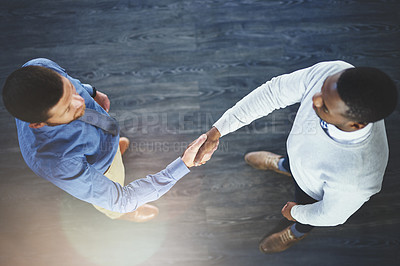 Buy stock photo High angle shot of two businesspeople shaking hands in an office