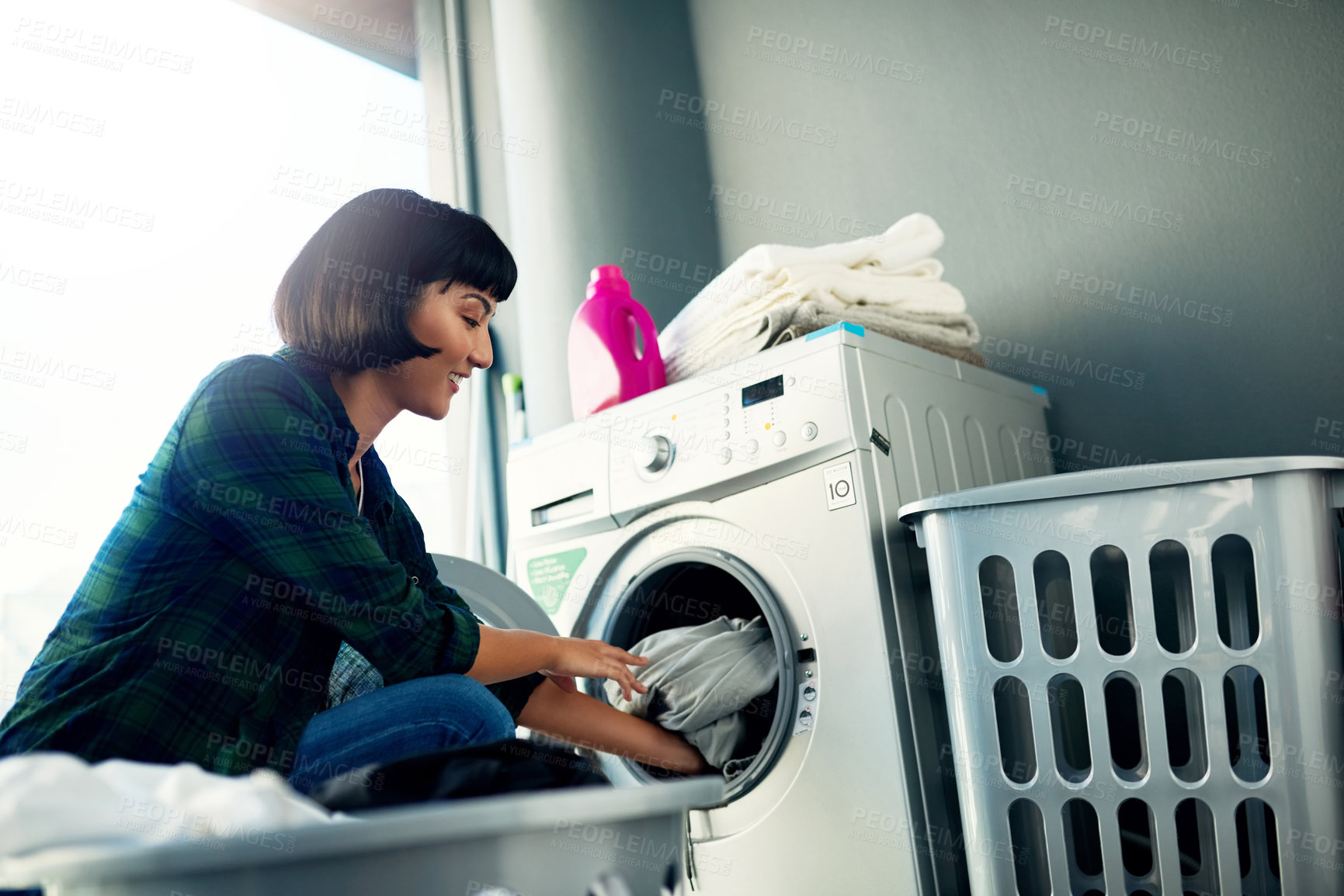 Buy stock photo Shot of a young woman doing her laundry at home