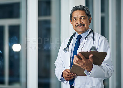 Buy stock photo Portrait of a happy mature doctor holding a clipboard in a hospital