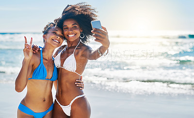 Buy stock photo Shot of two young women taking selfies together at the beach