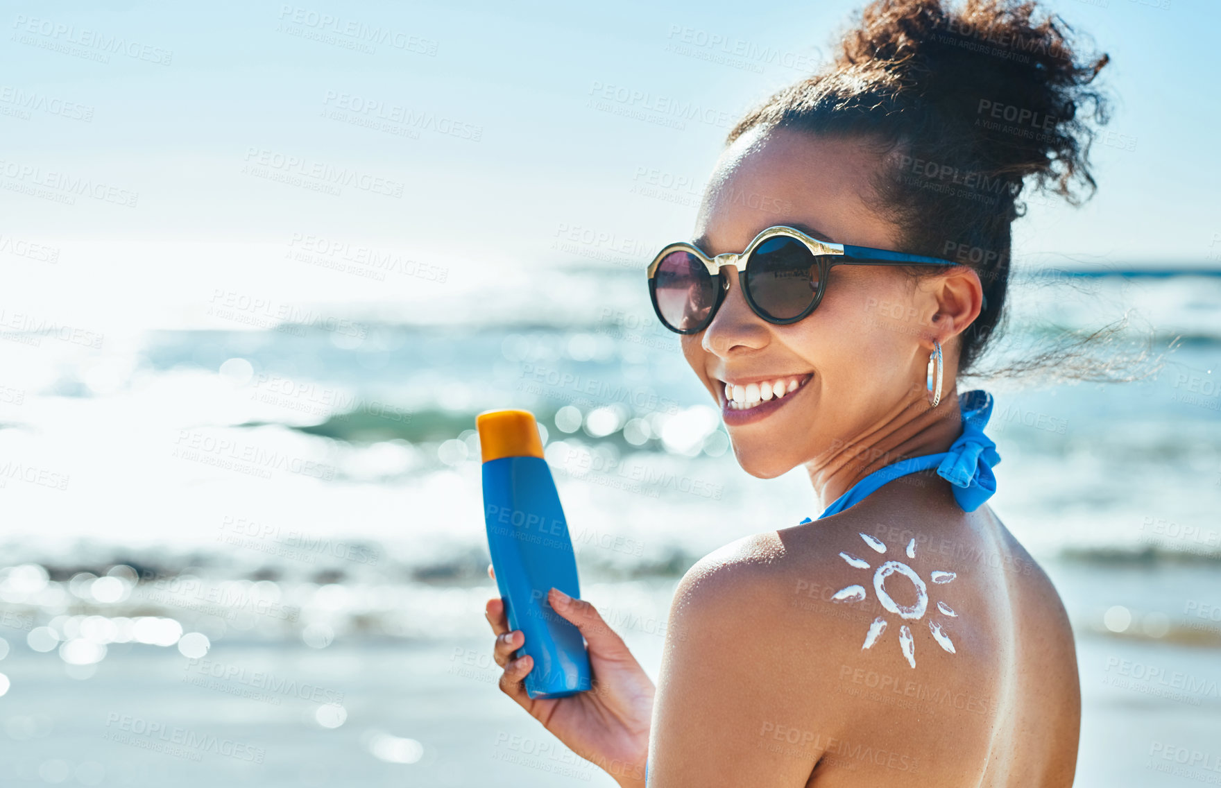 Buy stock photo Portrait of a beautiful young woman with a sun drawn on her shoulder with sunscreen at the beach