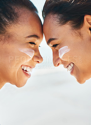 Buy stock photo Shot of two beautiful young women at the beach with sunscreen on their faces smiling at each other