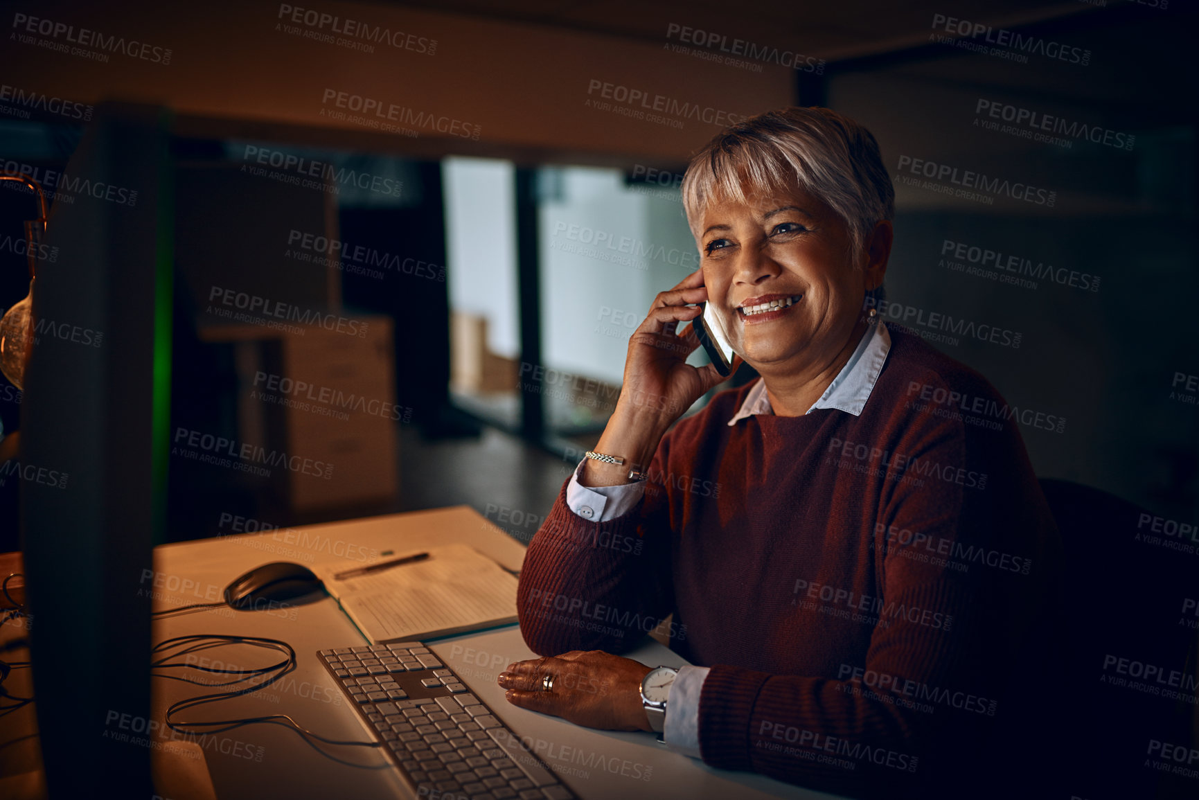 Buy stock photo Shot of a mature businesswoman talking on a cellphone while working late in an office