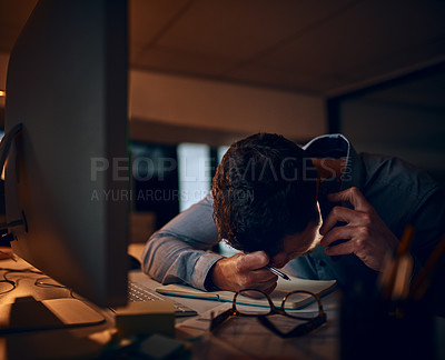 Buy stock photo Shot of a young businessman looking stressed out while talking on a cellphone in an office