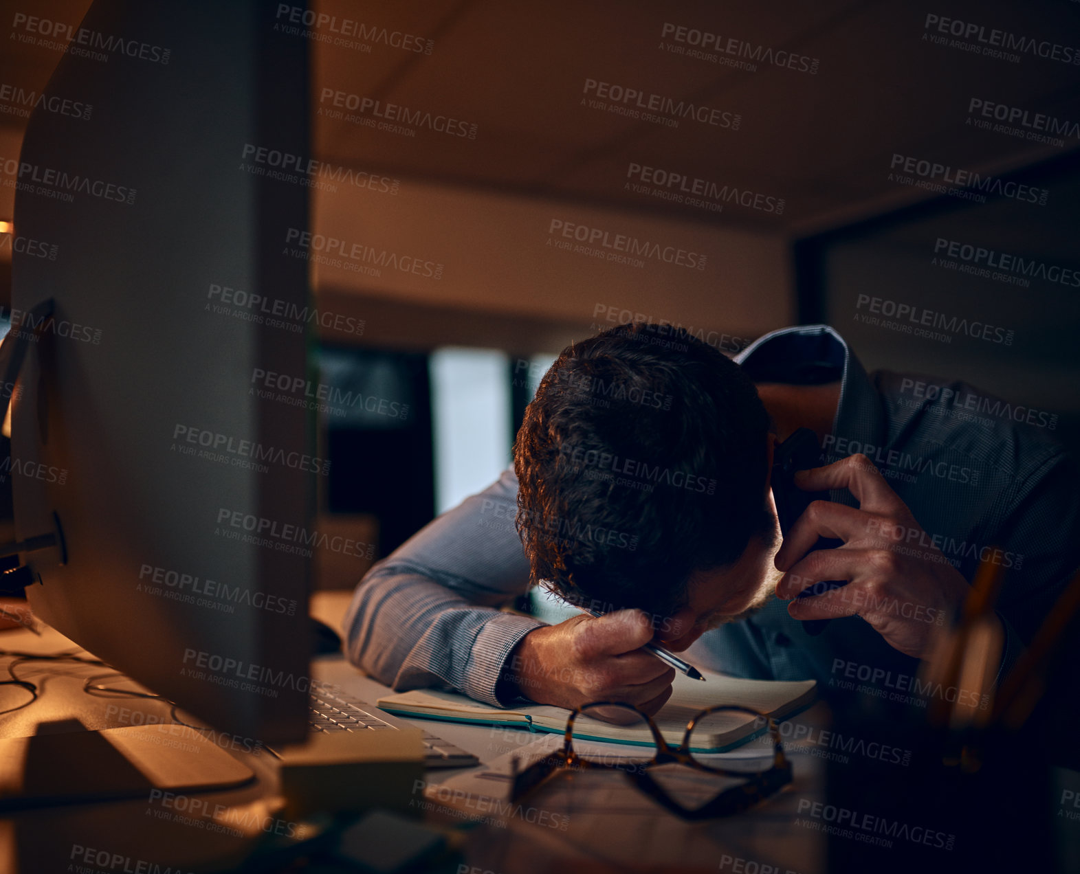 Buy stock photo Shot of a young businessman looking stressed out while talking on a cellphone in an office