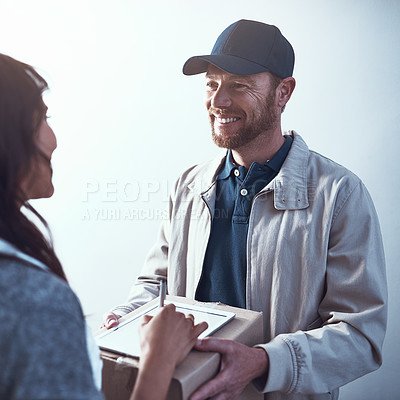 Buy stock photo Shot of a cheerful delivery man handing over a package to a customer and letting them sign on a digital tablet inside a building