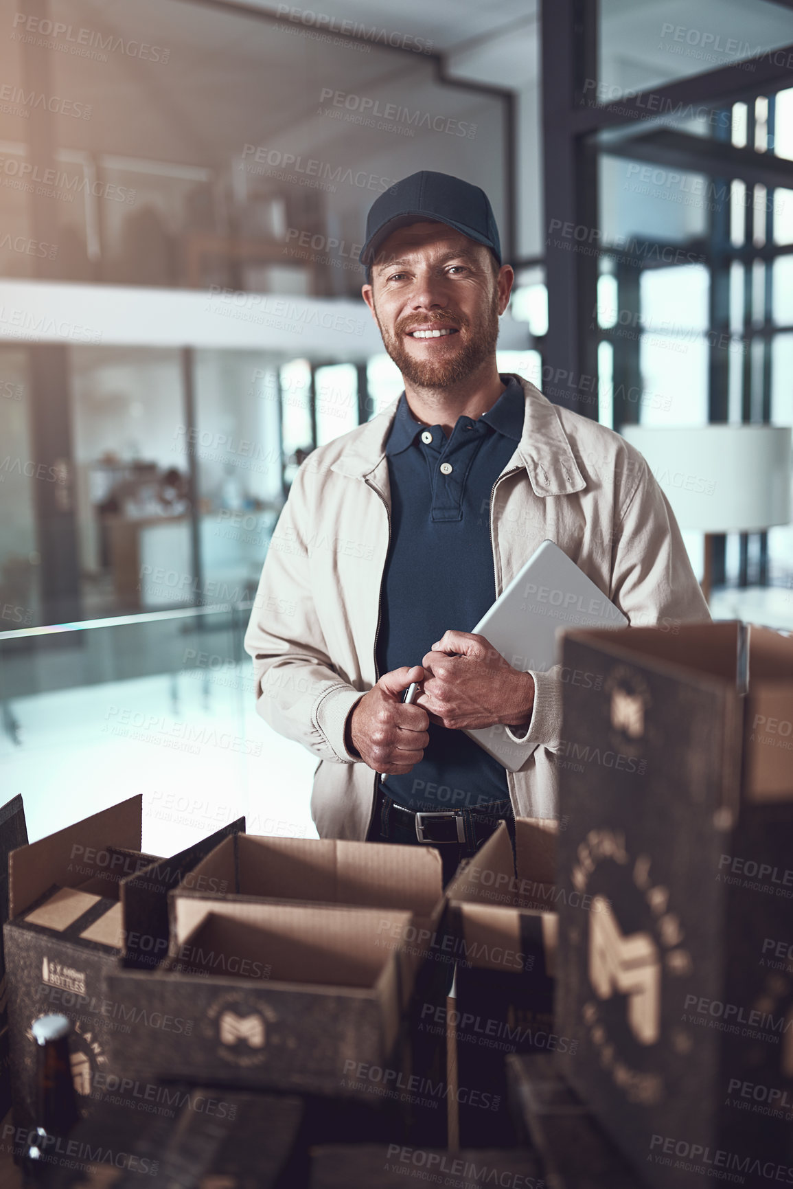 Buy stock photo Portrait of a cheerful young man packing boxes on top of each other inside of a office building during the day