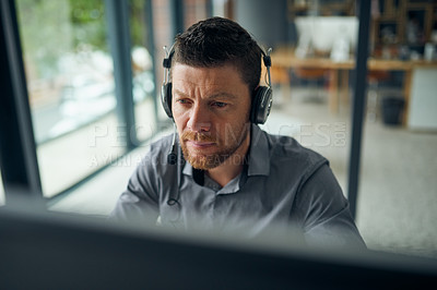 Buy stock photo Shot of a mature man working on a computer in a call centre