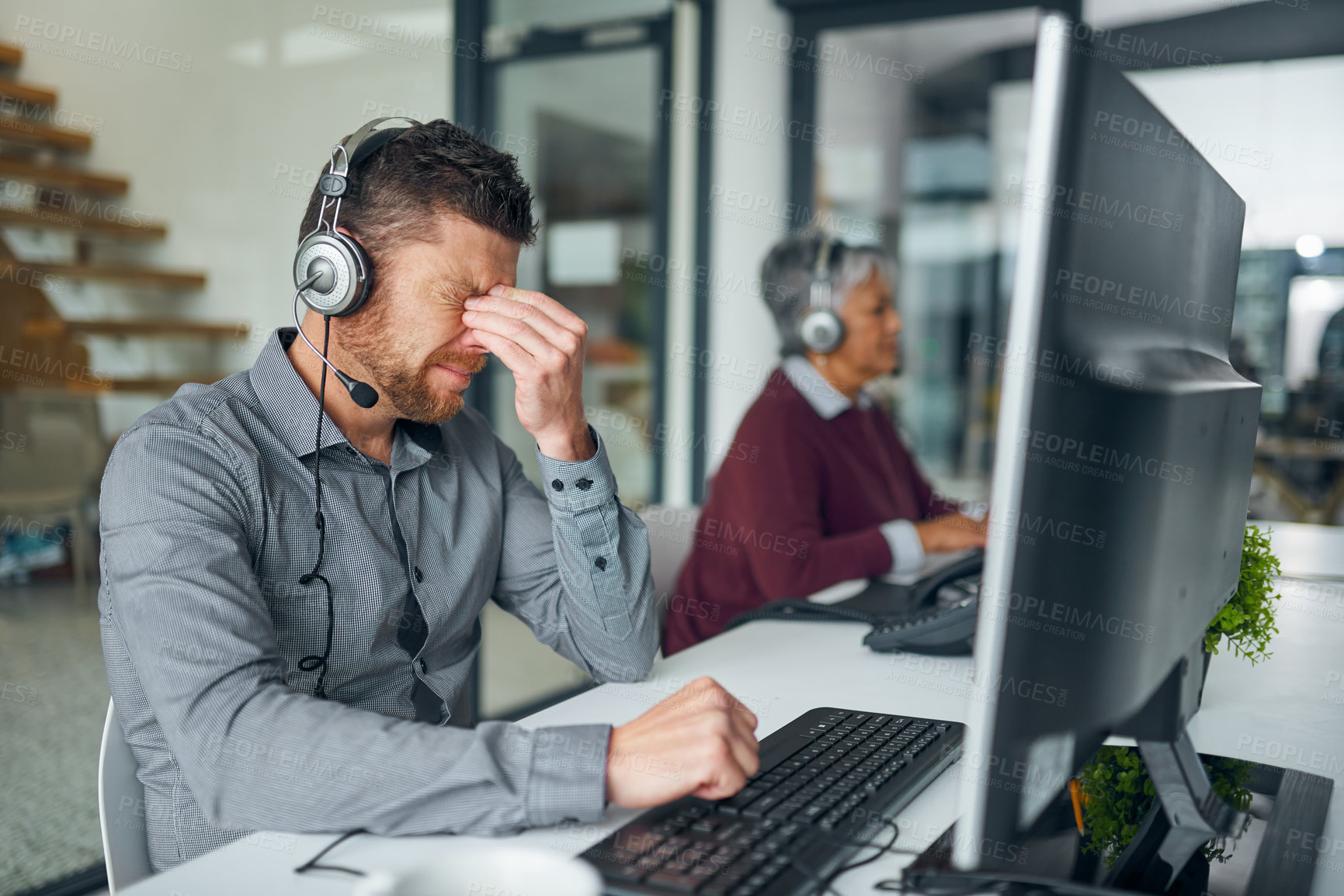 Buy stock photo Shot of a mature man looking stressed out while working on a computer in a call centre