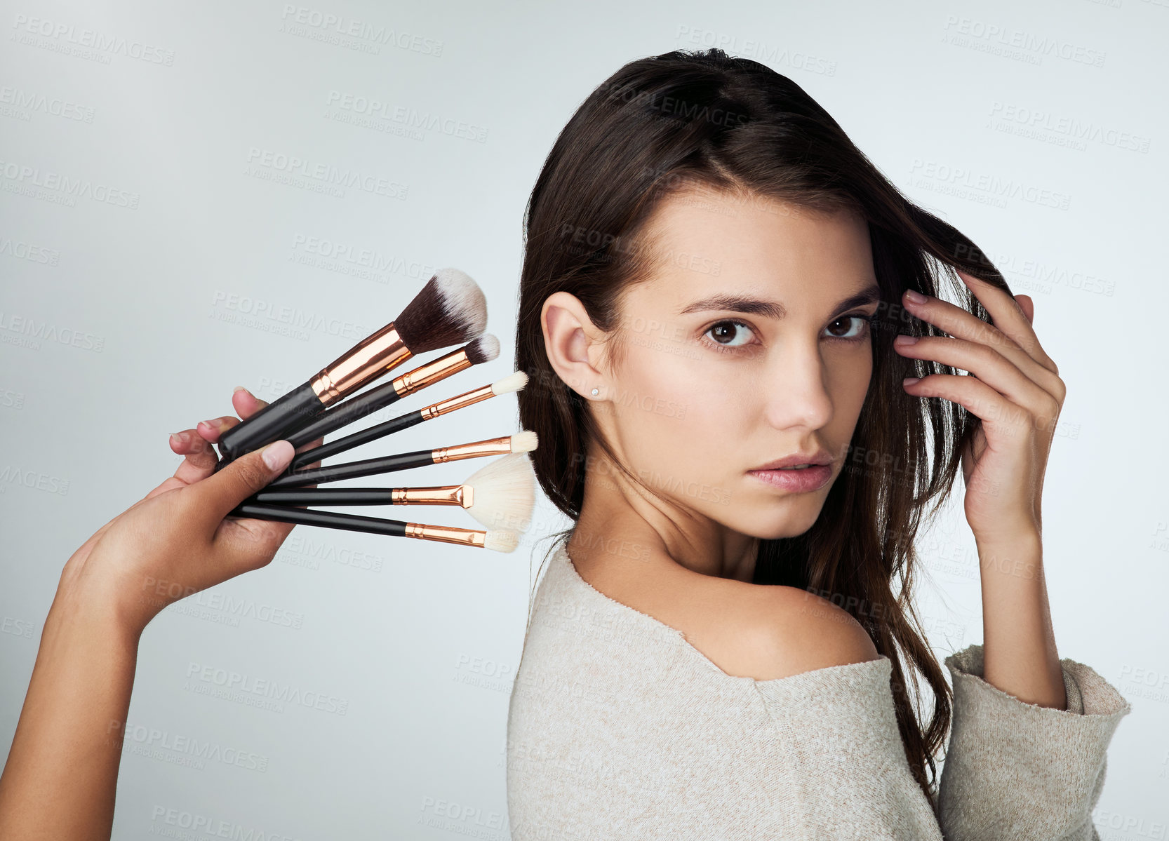 Buy stock photo Beauty, makeup brush and face of a woman in studio with a natural glow. Portrait of a female person on a grey background with a hand for cosmetology tools, powder cosmetics and facial skin care