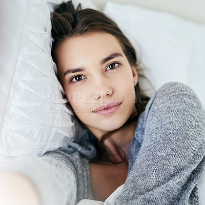 Buy stock photo Portrait of an attractive young woman taking a self portrait with her cellphone while lying in bed at home