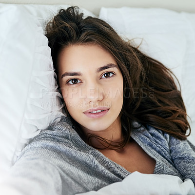 Buy stock photo Portrait of an attractive young woman taking a self portrait with her cellphone while lying in bed at home