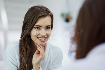 Buy stock photo Shot of an attractive young woman looking into a mirror with her hand touching her chin at home during the day