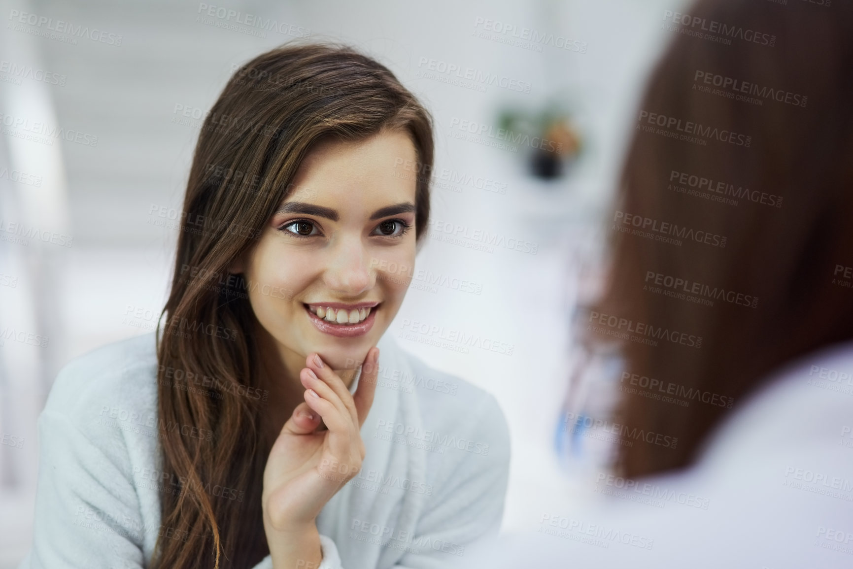 Buy stock photo Shot of an attractive young woman looking into a mirror with her hand touching her chin at home during the day
