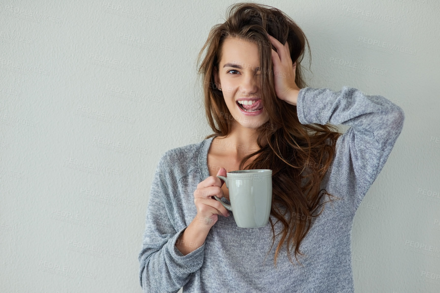 Buy stock photo Studio shot of an attractive young woman holding the side of her head while drinking coffee against a white background