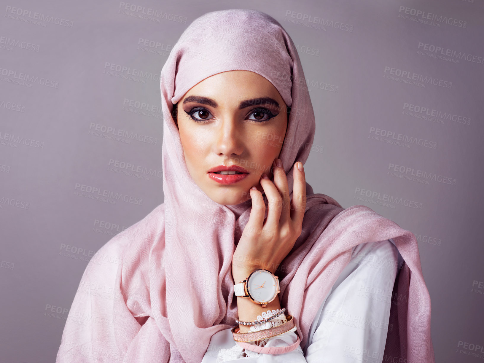 Buy stock photo Studio portrait of a cheerful young woman wearing a colorful head scarf while posing against a grey background