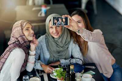 Buy stock photo Shot of a group of women taking selfies with a mobile phone in a cafe