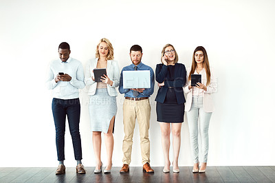 Buy stock photo Shot of a group of work colleagues standing next to each other while using electronic devices against a white background