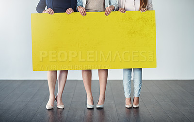 Buy stock photo Cropped studio shot of a group of businesswomen holding up a blank yellow placard