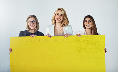 Buy stock photo Studio shot of a group of businesswomen holding up a blank yellow placard