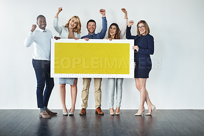 Buy stock photo Studio shot of a group of businesspeople holding up a blank yellow placard and cheering