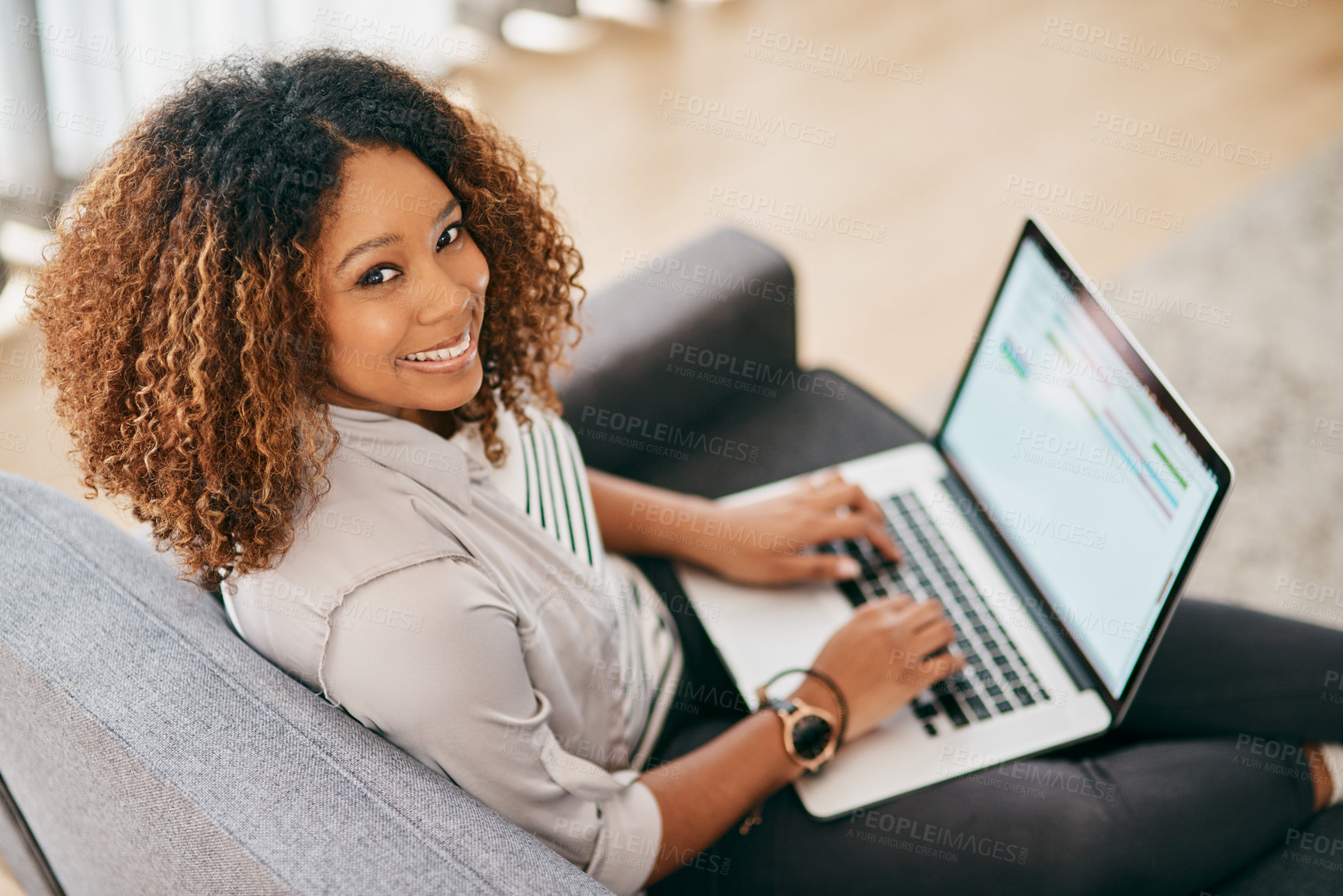 Buy stock photo Portrait of a cheerful young woman working on her laptop while being seated on a couch at home