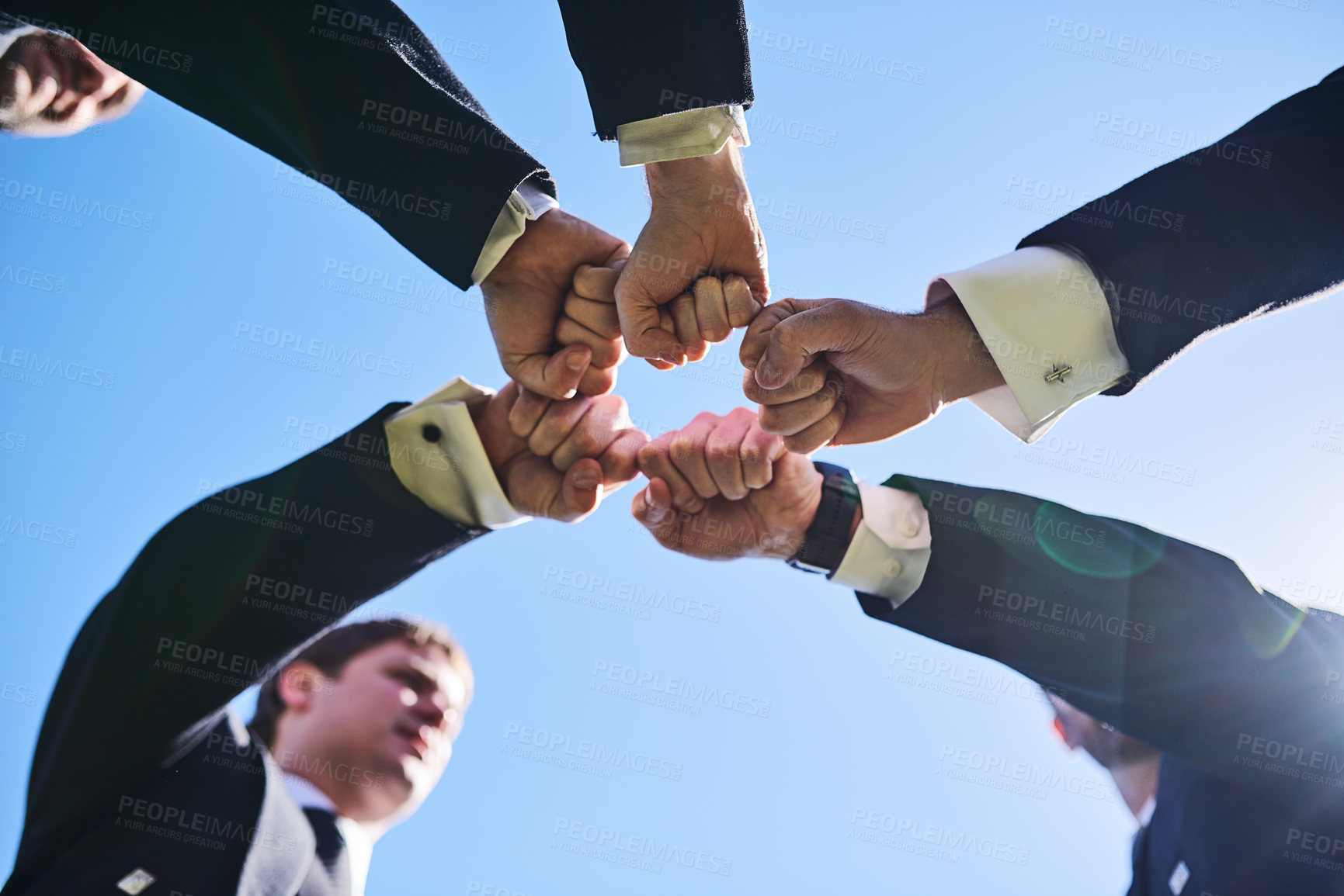 Buy stock photo Low angle shot of a group of well dressed men forming a huddle and giving each other a fist pump outside during the day