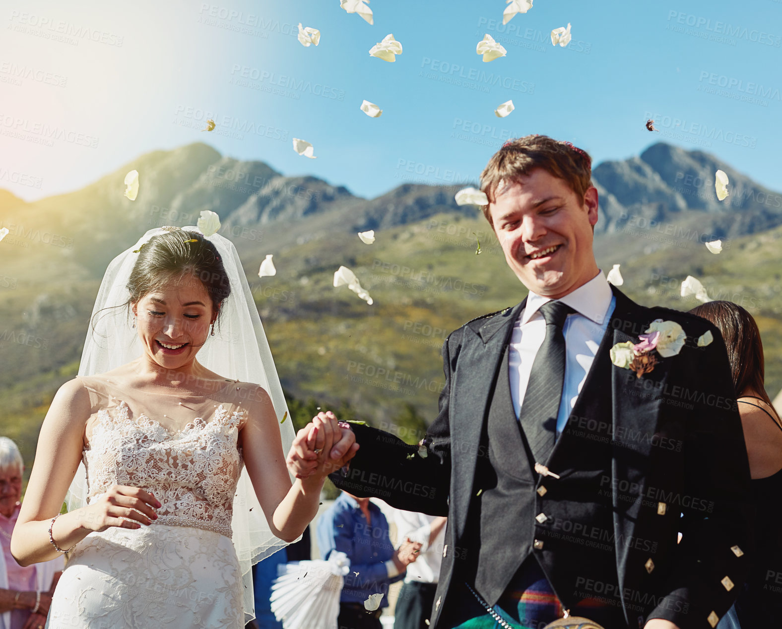 Buy stock photo Couple, holding hands and outdoor flower confetti for love, reception and eternal partnership. People, support and family clapping for marriage commitment, celebrate event and wedding in Scotland