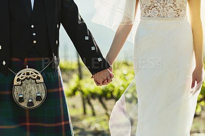 Buy stock photo Shot of an unrecognizable bride and groom holding hands and walking together outside during the day