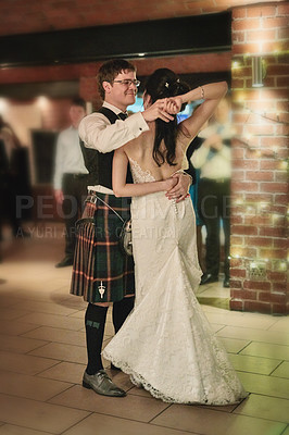 Buy stock photo Shot of a cheerful bride and groom having the first dance of the evening together on the dance floor inside of a building