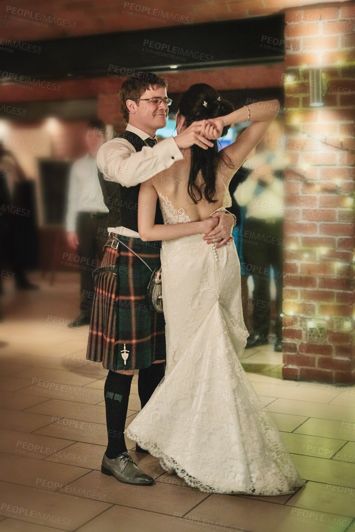 Buy stock photo Shot of a cheerful bride and groom having the first dance of the evening together on the dance floor inside of a building