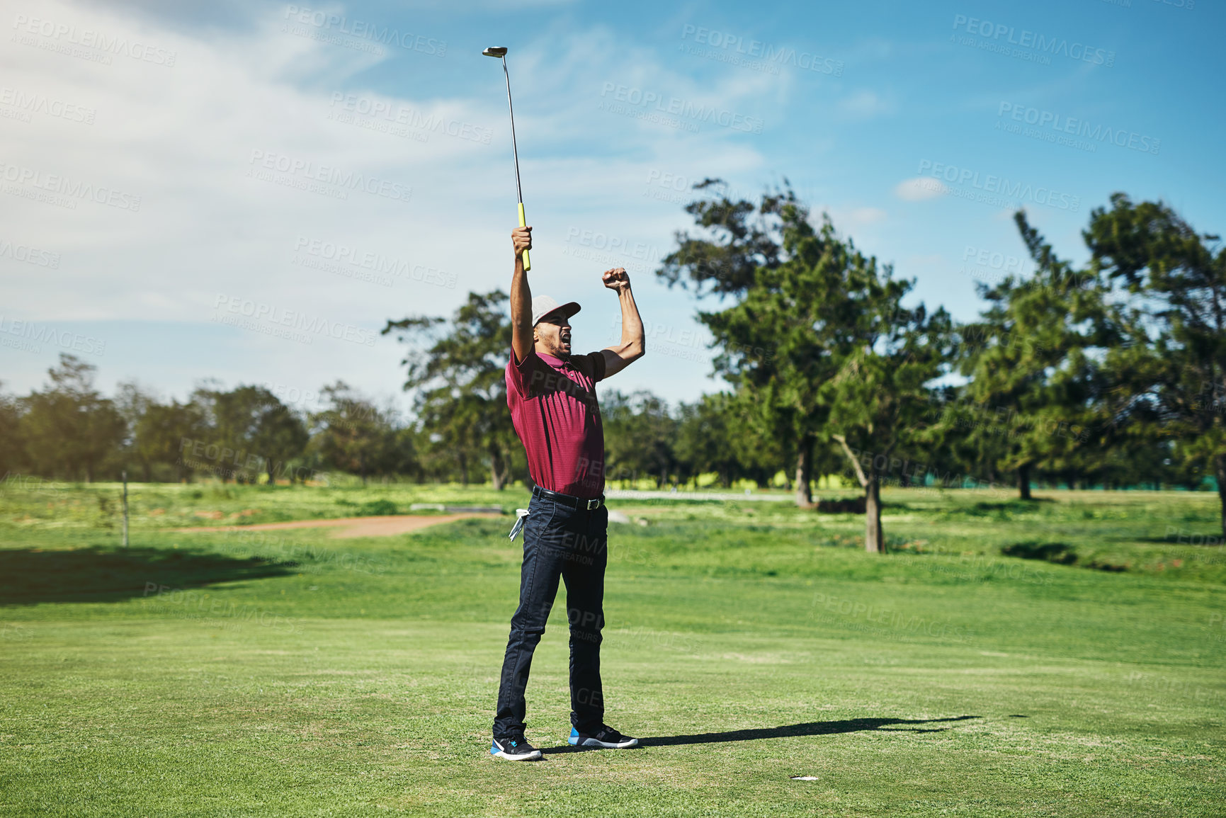 Buy stock photo Shot of a cheerful young male golfer lifting up his hands in success of playing a good shot outside during the day