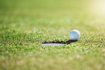 Buy stock photo Closeup shot of a golf ball on the edge of a hole outside on a golf course during the day