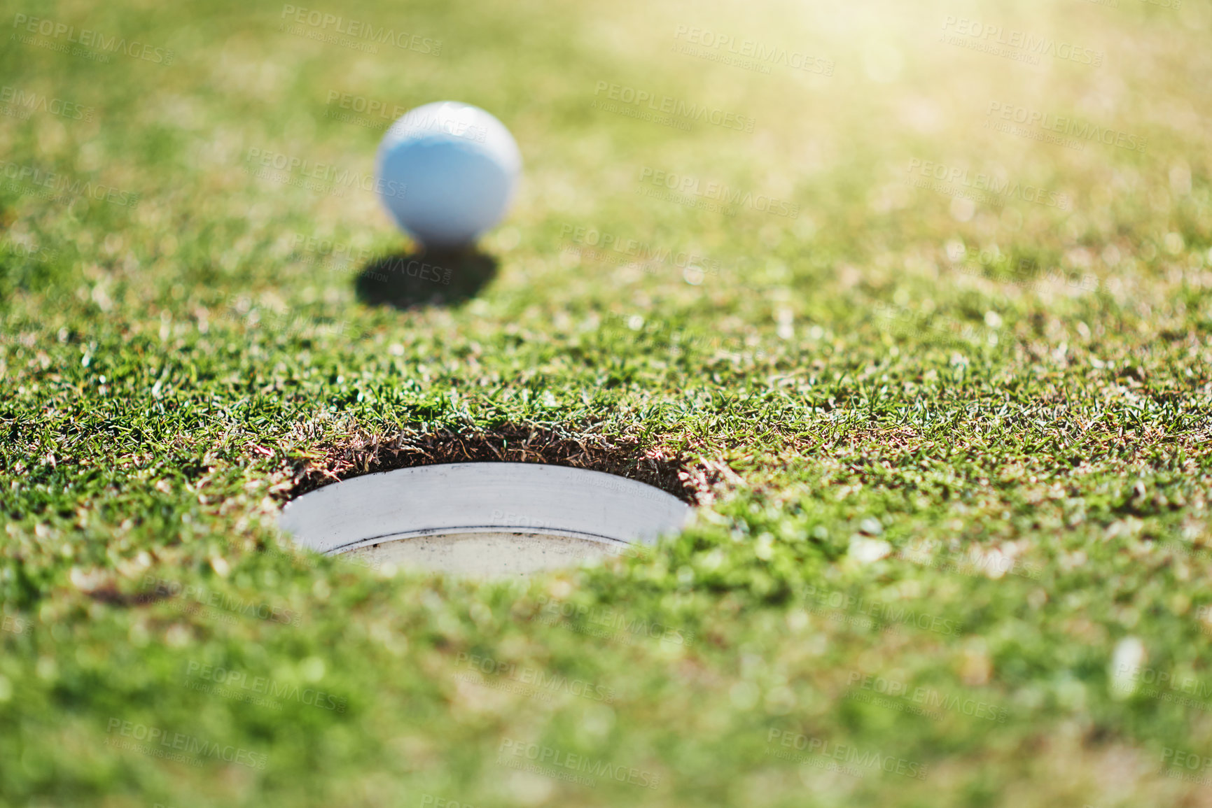 Buy stock photo Closeup shot of a golf ball on the edge of a hole outside on a golf course during the day