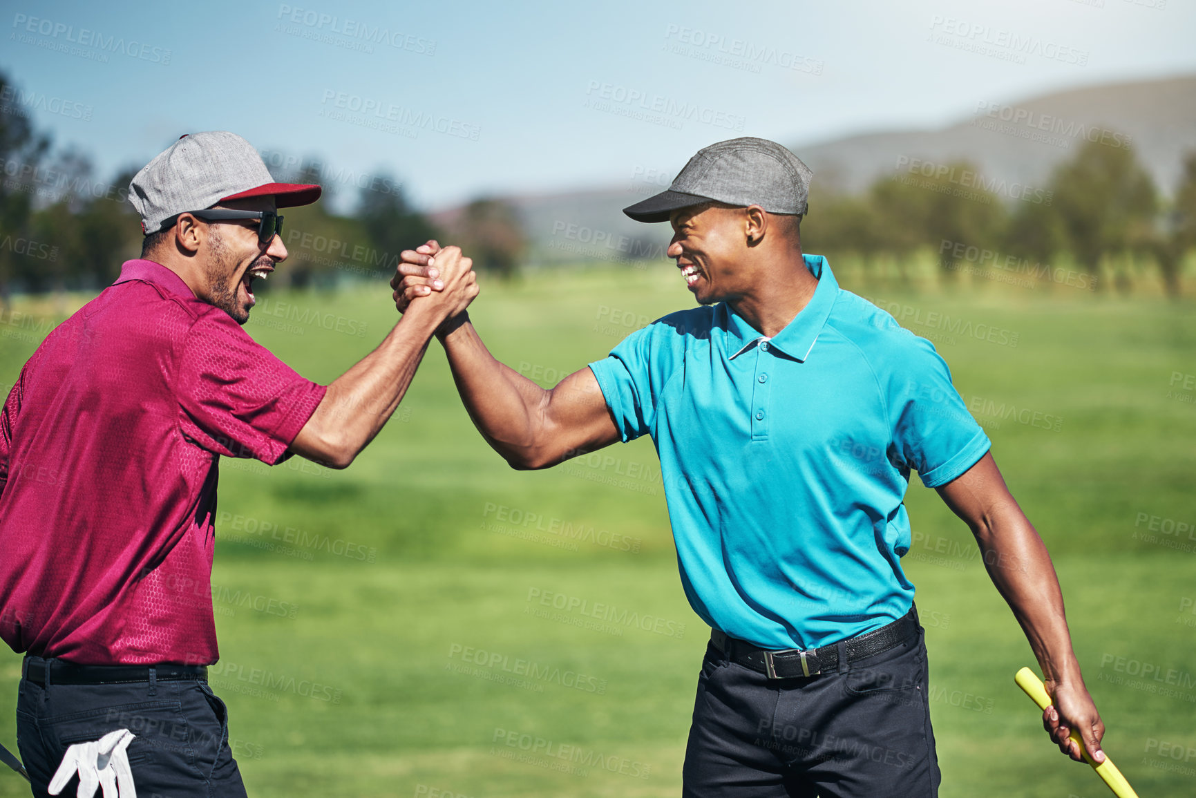 Buy stock photo Shot of two cheerful young male golfers engaging in a handshake after a great shot on the golf course