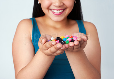 Buy stock photo Studio shot of a cute young girl holding a handful of colorful jelly beans