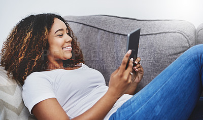 Buy stock photo Shot of an attractive young woman using a digital tablet at home