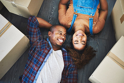 Buy stock photo High angle shot of an attractive young couple laying on the floor in their new home